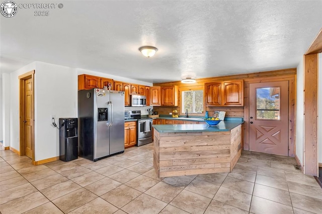 kitchen with stainless steel appliances, sink, light tile patterned floors, and kitchen peninsula