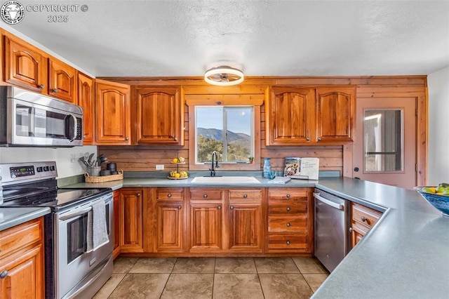 kitchen with stainless steel appliances, light tile patterned flooring, sink, and a textured ceiling