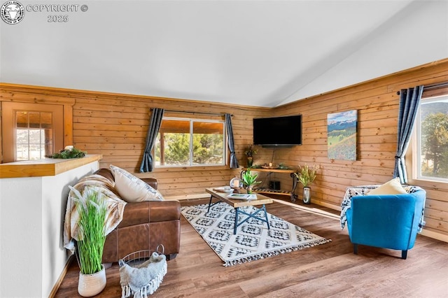 living room with plenty of natural light, hardwood / wood-style floors, lofted ceiling, and wooden walls