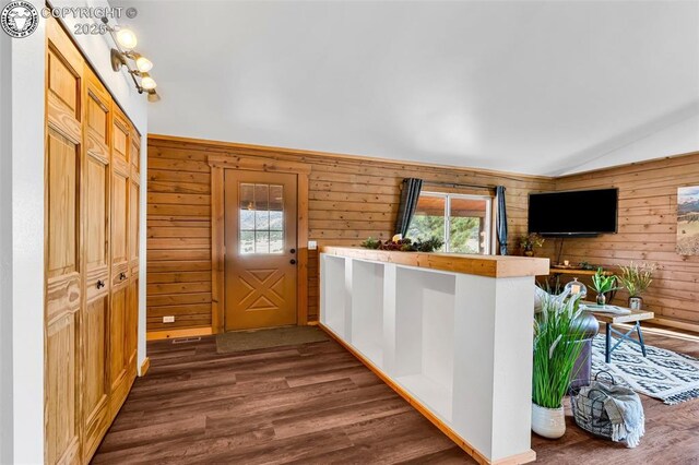 interior space with dark hardwood / wood-style flooring, lofted ceiling, and wood walls