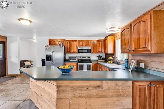 kitchen with sink, light tile patterned floors, stainless steel appliances, and kitchen peninsula