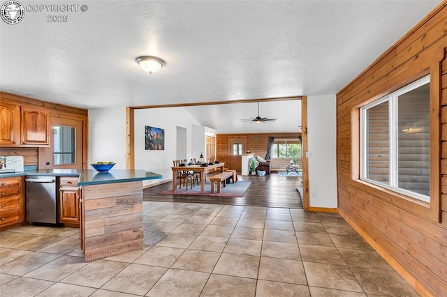 kitchen with brick wall, stainless steel dishwasher, ceiling fan, and light tile patterned floors