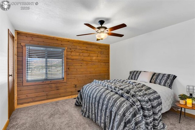 carpeted bedroom featuring ceiling fan and wood walls