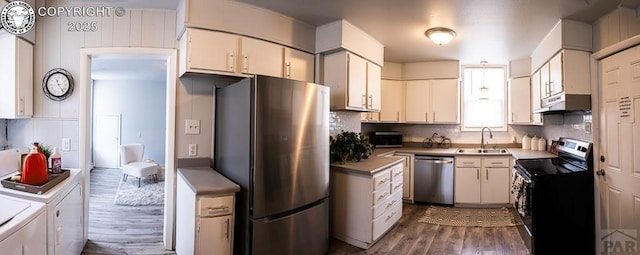 2723 3rd Ave, Pueblo, CO 81003 - kitchen featuring under cabinet range hood, a sink, wood finished floors, washing machine and clothes dryer, and appliances with stainless steel finishes