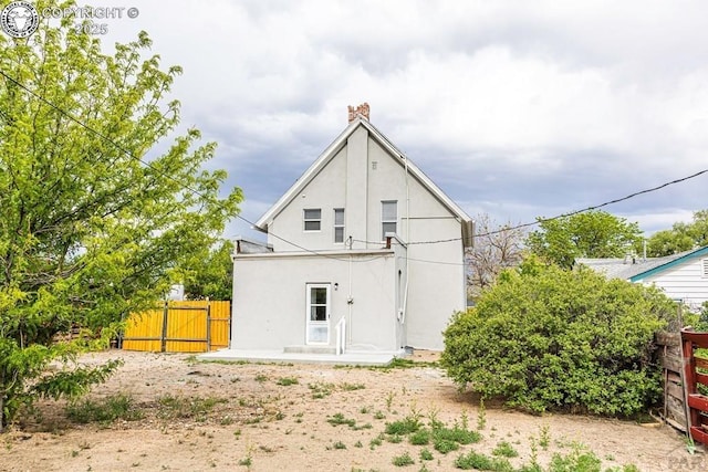 2723 3rd Ave, Pueblo, CO 81003 - back of house featuring a chimney, stucco siding, fence, and a gate