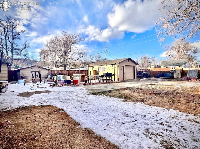 yard covered in snow featuring a garage and a storage shed