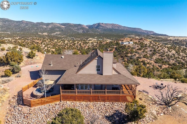 rear view of house with roof with shingles and a deck with mountain view