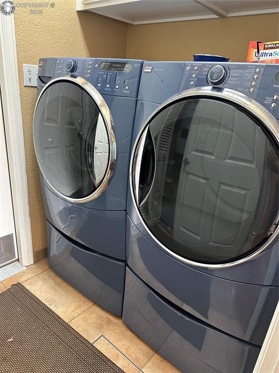 laundry area with light tile patterned floors, a textured wall, laundry area, separate washer and dryer, and mail area