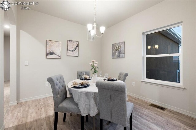 dining space featuring light hardwood / wood-style floors and a notable chandelier