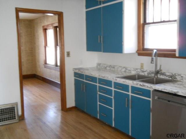 kitchen featuring sink, stainless steel dishwasher, hardwood / wood-style floors, and blue cabinets