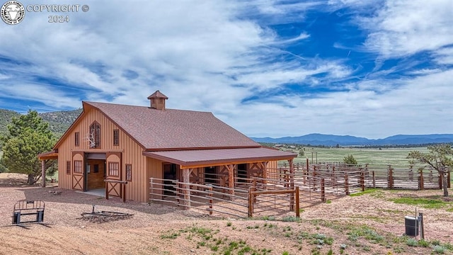 view of horse barn with a mountain view and a rural view