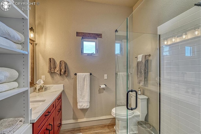 bathroom with a shower with door, vanity, hardwood / wood-style flooring, and toilet