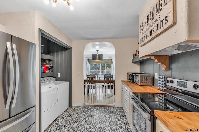 kitchen with premium range hood, wooden counters, stainless steel appliances, washing machine and dryer, and white cabinets