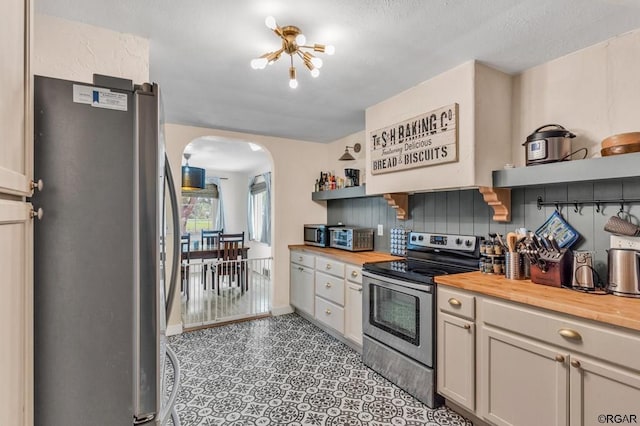 kitchen featuring appliances with stainless steel finishes, butcher block countertops, and decorative backsplash