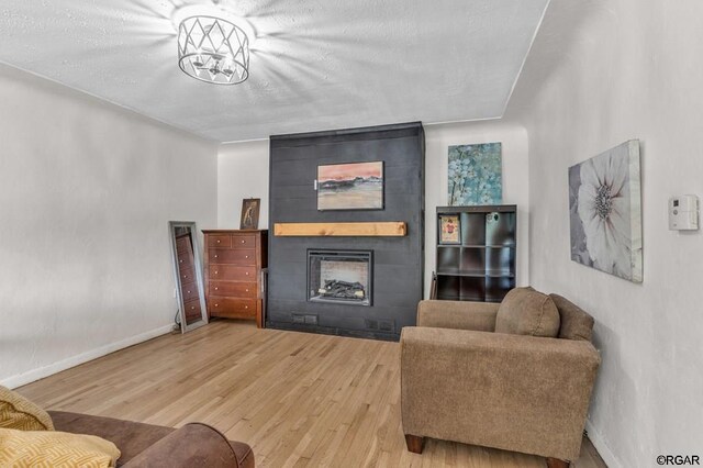 living room with wood-type flooring, a textured ceiling, and a fireplace