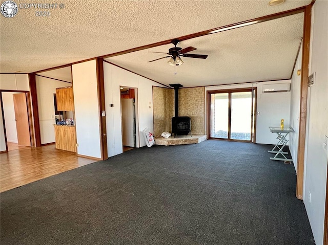 unfurnished living room featuring carpet floors, lofted ceiling, a wood stove, and a wall mounted air conditioner