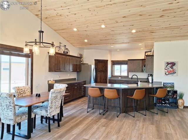 201 Fox Run, Silver Cliff, CO 81252 - kitchen with dark brown cabinetry, wooden ceiling, a peninsula, a kitchen bar, and light wood finished floors