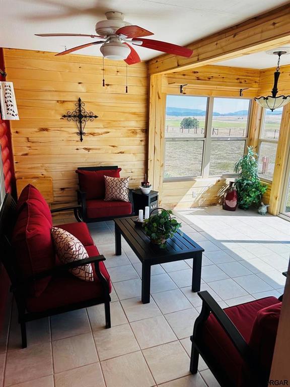 2 Inverness Ave, Westcliffe, CO 81252 - living area with a ceiling fan, wooden walls, light tile patterned flooring, and beamed ceiling