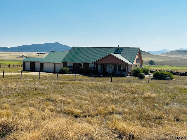 back of property featuring a rural view, a mountain view, and a garage