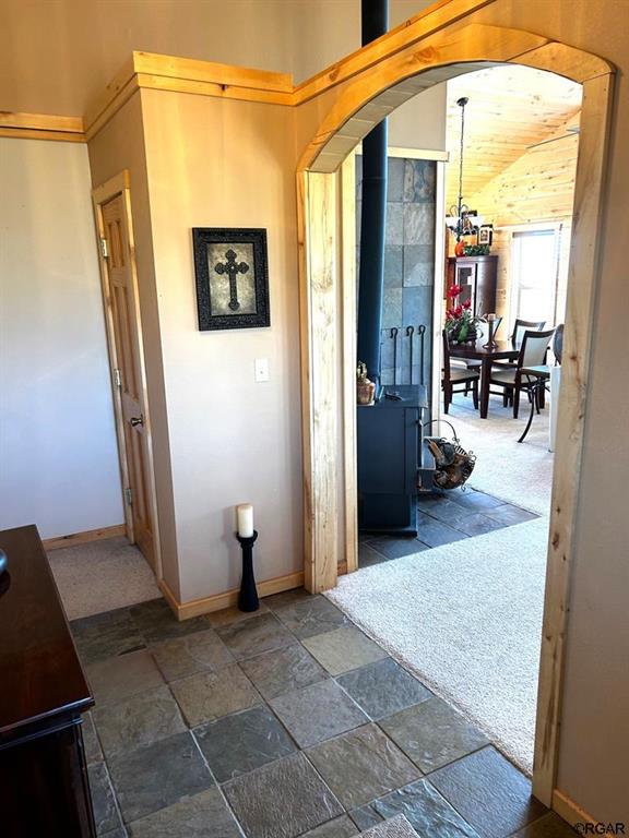 2 Inverness Ave, Westcliffe, CO 81252 - entrance foyer with a wood stove, arched walkways, stone tile floors, and baseboards