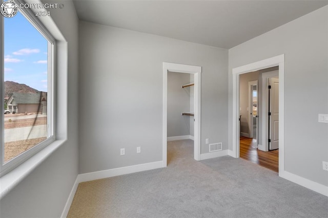 unfurnished bedroom featuring a mountain view, a spacious closet, light colored carpet, and a closet