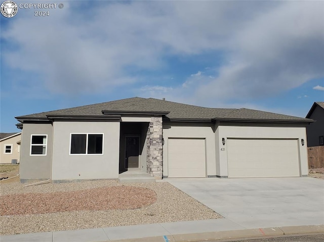 prairie-style home featuring concrete driveway, an attached garage, and stucco siding