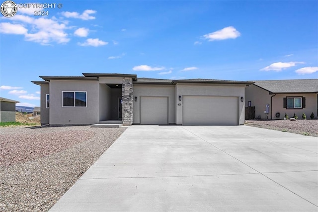 prairie-style house with a garage, driveway, and stucco siding