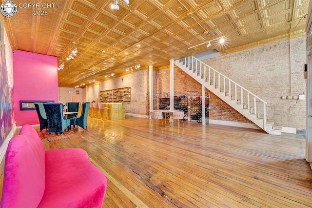 122 W Main St, Florence, CO 81226 - living area with brick wall, an ornate ceiling, wood-type flooring, stairway, and baseboards