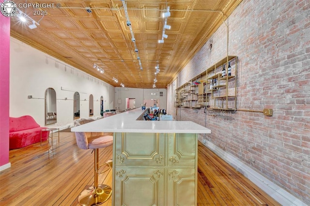 122 W Main St, Florence, CO 81226 - bar area with brick wall, light wood-type flooring, an ornate ceiling, and baseboards