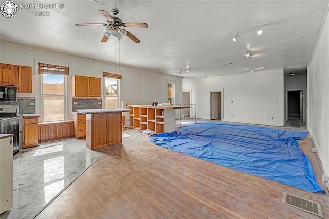 122 W Main St, Florence, CO 81226 - kitchen with black microwave, a kitchen island, range, brown cabinetry, and backsplash