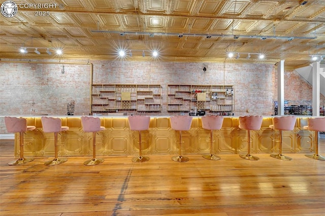 122 W Main St, Florence, CO 81226 - unfurnished dining area featuring brick wall, an ornate ceiling, hardwood / wood-style floors, and a dry bar