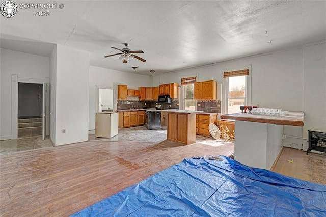 122 W Main St, Florence, CO 81226 - kitchen with black microwave, brown cabinets, a center island, tasteful backsplash, and a ceiling fan