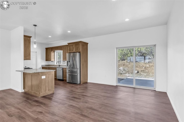 kitchen with dark wood-type flooring, stainless steel appliances, light stone counters, decorative light fixtures, and kitchen peninsula