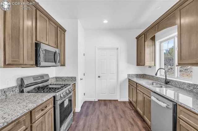 kitchen featuring stainless steel appliances, dark hardwood / wood-style floors, light stone countertops, and sink