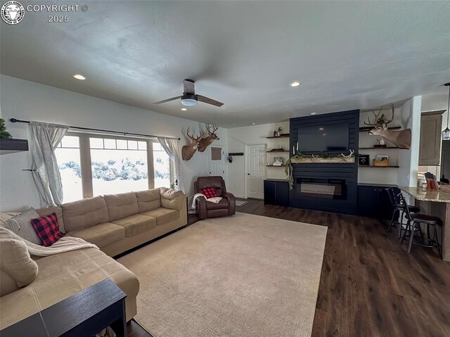 living room featuring ceiling fan, a fireplace, and dark hardwood / wood-style floors