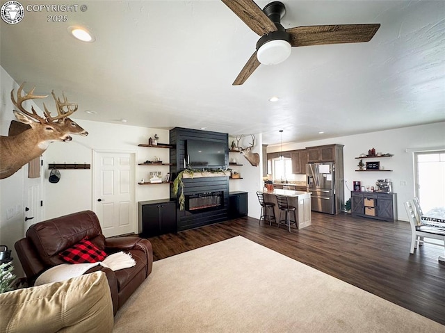 living room with a large fireplace, a wealth of natural light, dark hardwood / wood-style floors, and ceiling fan