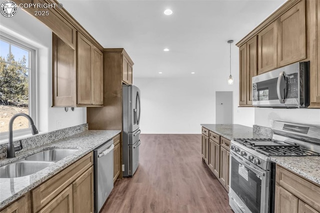 kitchen featuring sink, appliances with stainless steel finishes, dark hardwood / wood-style floors, pendant lighting, and light stone countertops