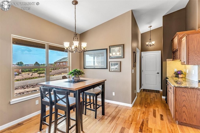 dining space featuring vaulted ceiling, light wood-type flooring, and an inviting chandelier