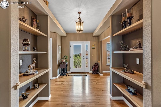 interior space featuring a notable chandelier, built in shelves, and light hardwood / wood-style flooring