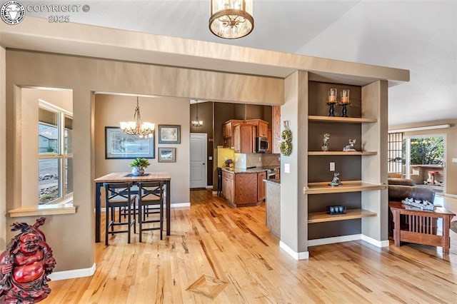 kitchen featuring pendant lighting, stainless steel appliances, built in shelves, a chandelier, and light wood-type flooring