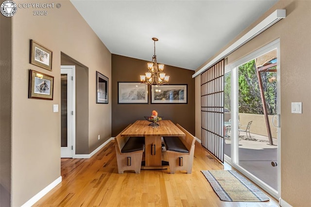 unfurnished dining area with vaulted ceiling, a notable chandelier, and light hardwood / wood-style flooring