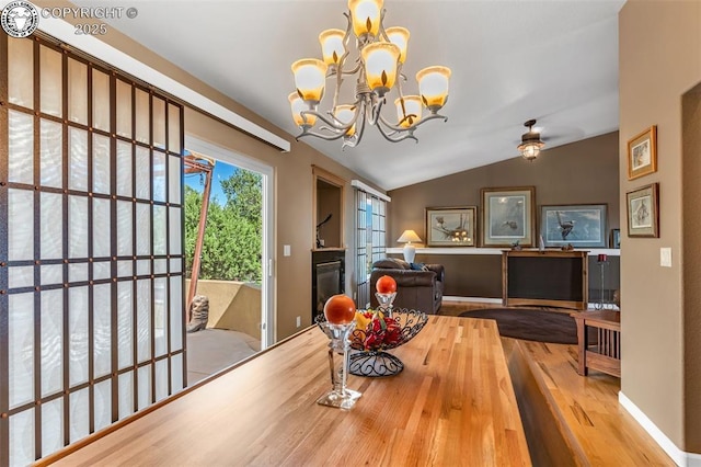 dining room with light hardwood / wood-style flooring, vaulted ceiling, and an inviting chandelier