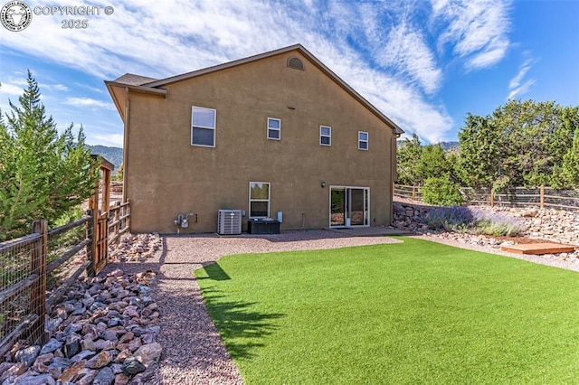 back of house featuring central AC unit and a lawn