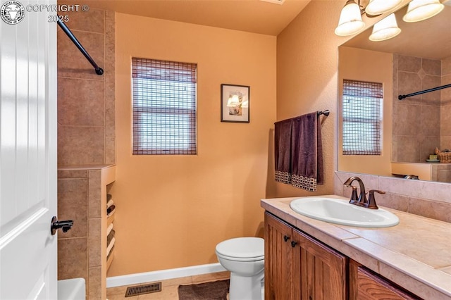 bathroom featuring tiled shower, vanity, toilet, and tile patterned flooring