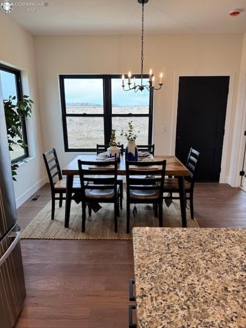 dining space with dark wood-type flooring, a chandelier, and a healthy amount of sunlight