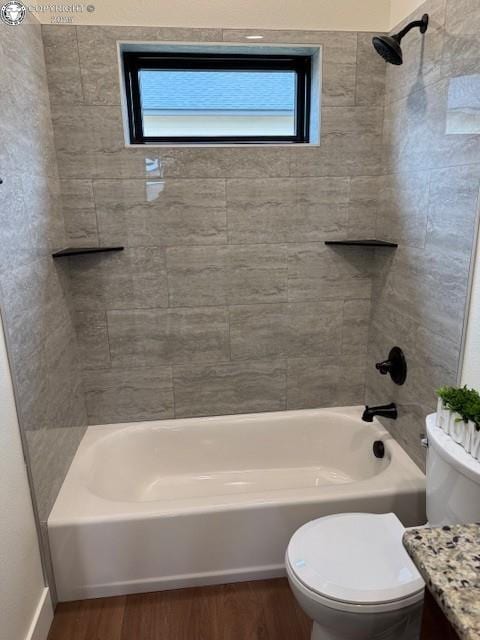 full bathroom featuring hardwood / wood-style flooring, tiled shower / bath combo, vanity, and toilet