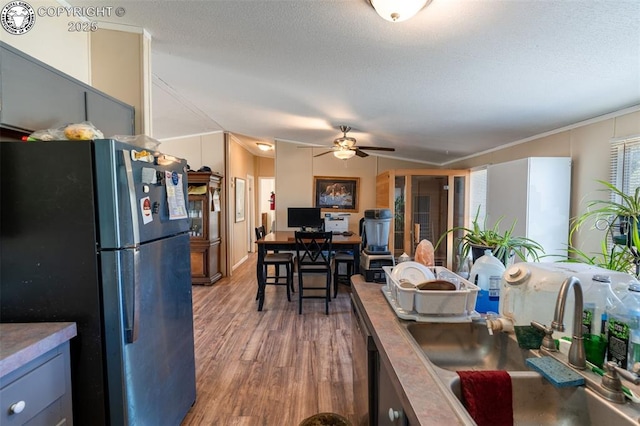 kitchen featuring sink, wood-type flooring, black refrigerator, ornamental molding, and ceiling fan