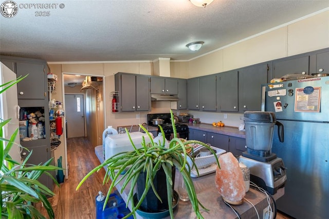 kitchen with refrigerator, a textured ceiling, dark hardwood / wood-style floors, gray cabinets, and black gas stove