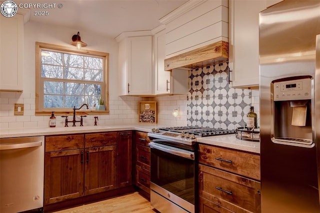 kitchen featuring tasteful backsplash, stainless steel appliances, light countertops, premium range hood, and a sink