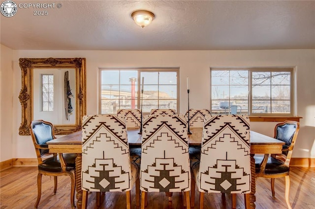 dining area with a textured ceiling, baseboards, and wood finished floors